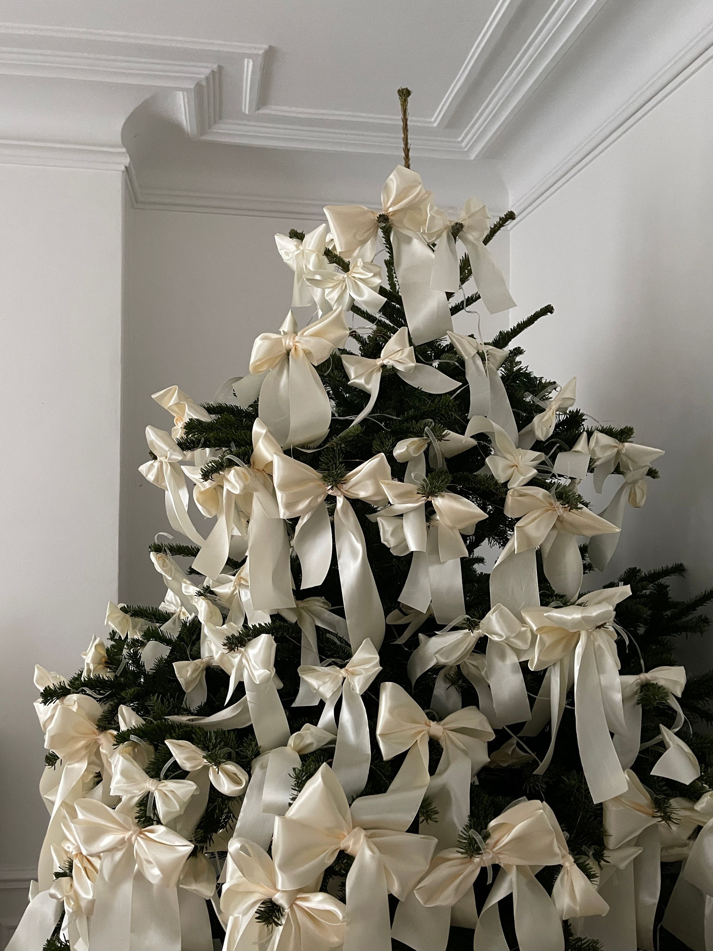 A Christmas tree dressed entirely in ivory satin bows in a panelled period room