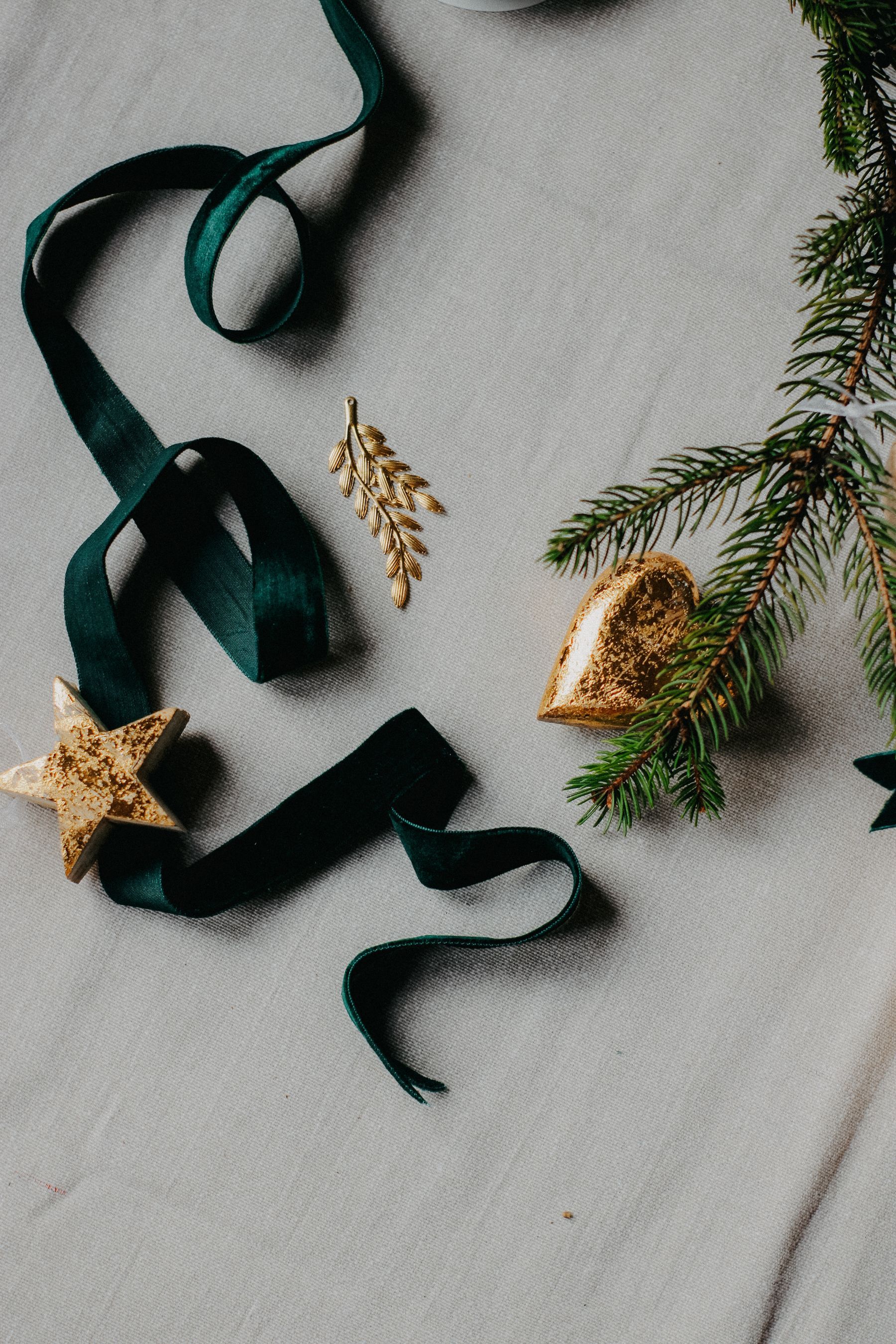 Deep green velvet ribbon, gold ornaments and pine on ivory linen